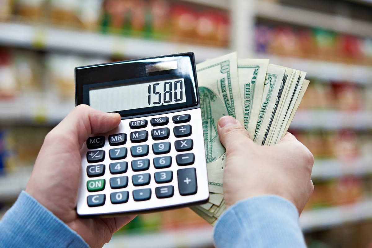 Man with dollars and calculator considers costs in store