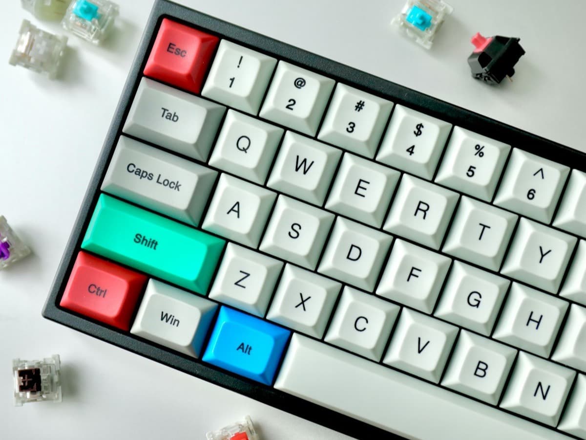 A compact keyboard with white and coloured keycaps surrounded by loose mechanical switches