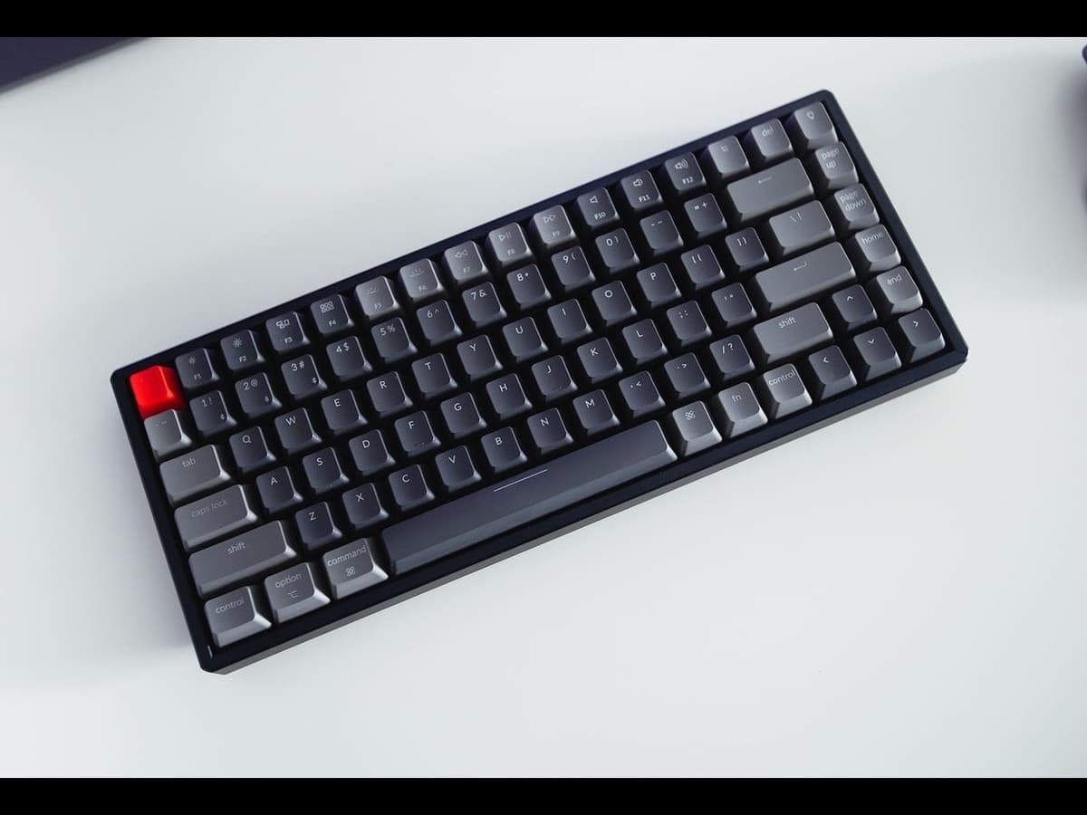 A compact grey-and-black keyboard beside a wireless mouse on a clean white desk