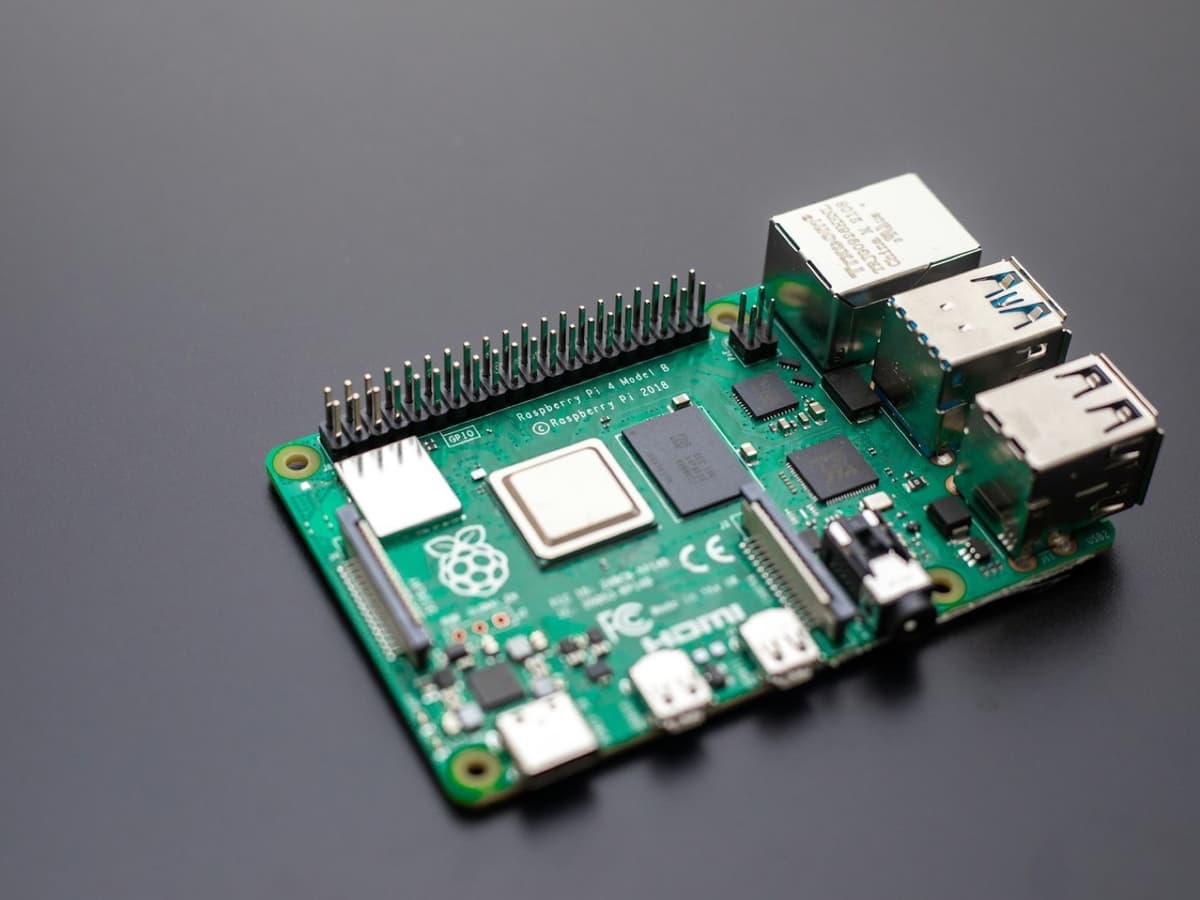 A Raspberry Pi single-board computer on a dark desk with its Ethernet and USB ports facing the camera