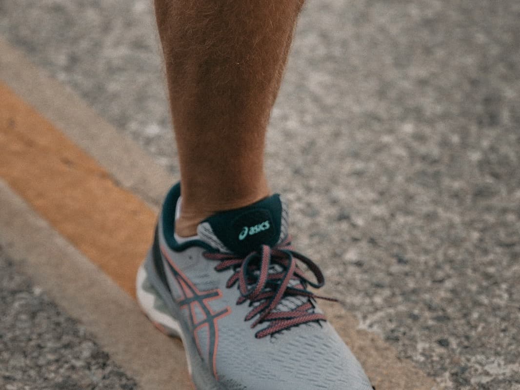 Close-up of a runner mid-stride in grey road-running shoes on asphalt