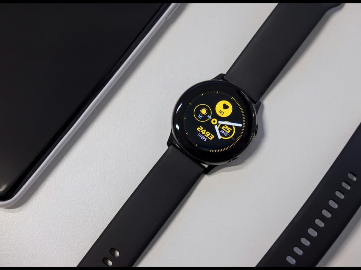 An affordable round smartwatch on a white surface showing a step count