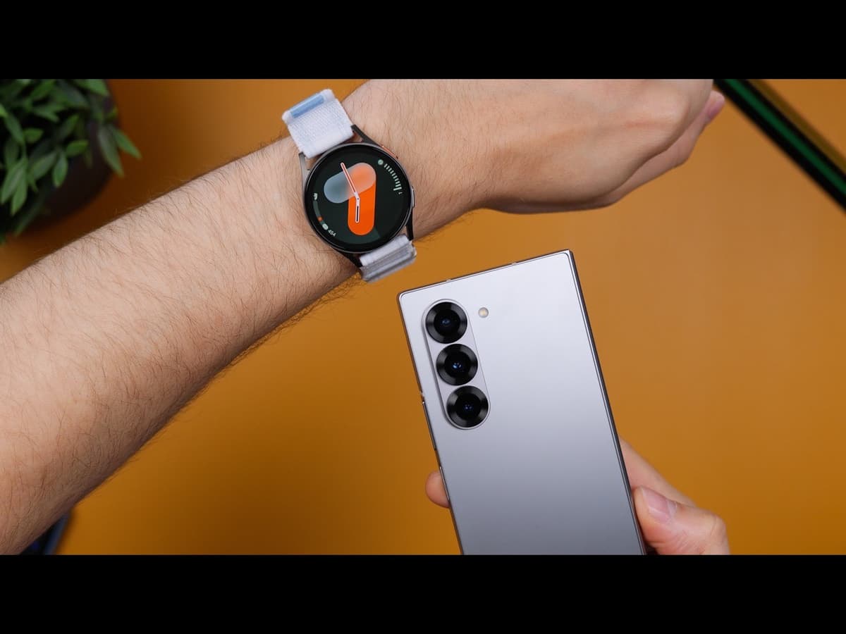 A round Android smartwatch on a wrist next to a Samsung phone