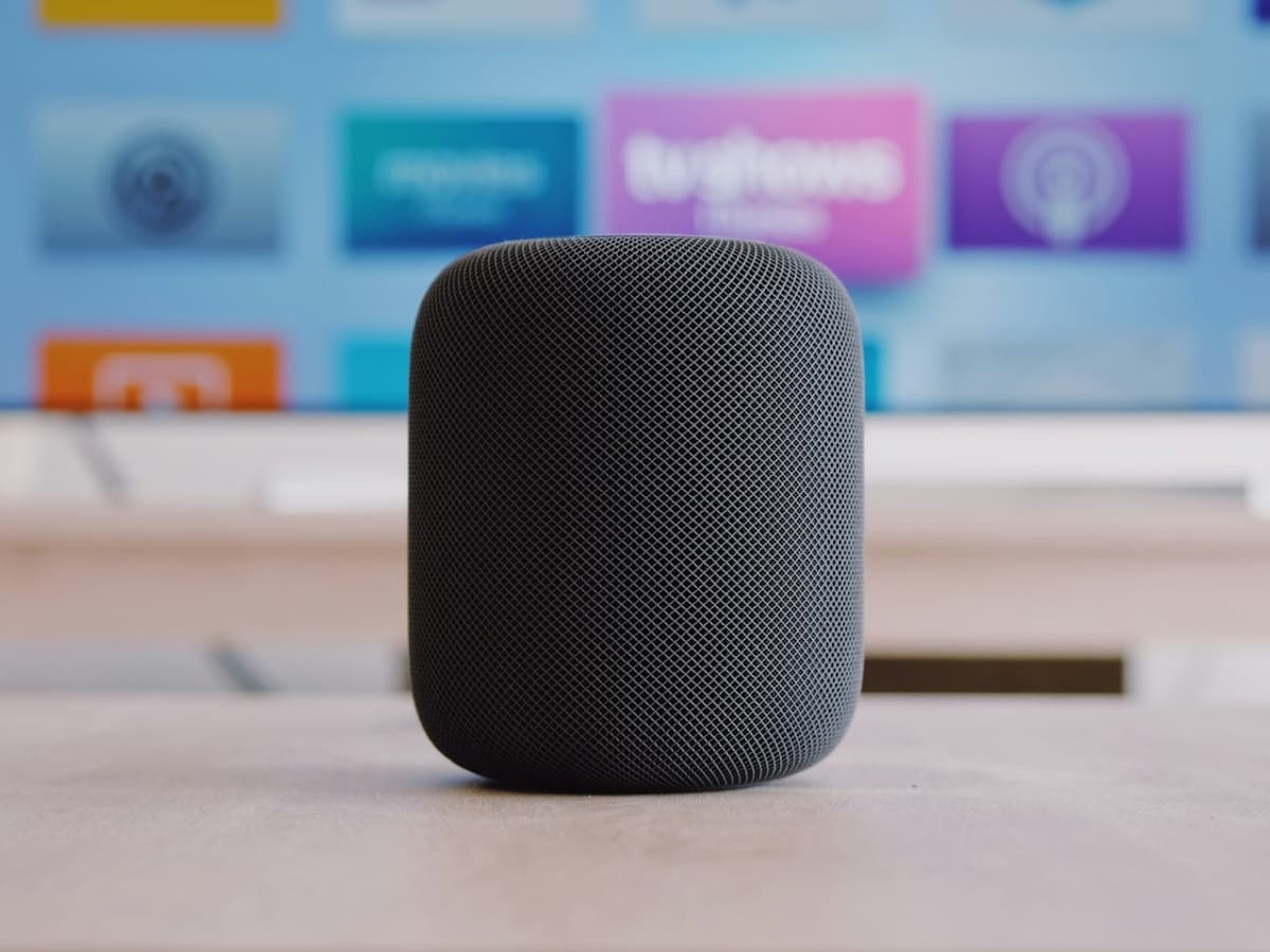 A cylindrical smart speaker on a table in front of a TV