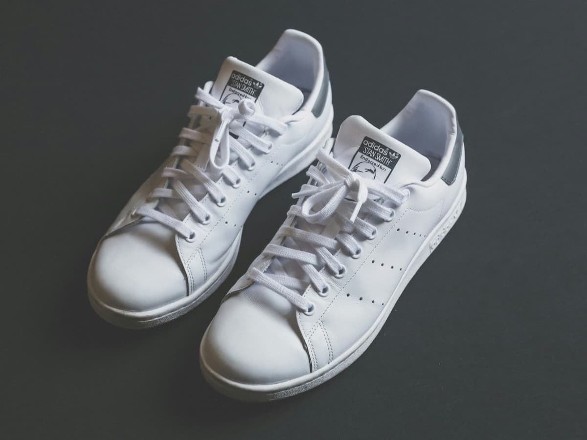 A pair of clean white leather low-top sneakers on a dark background