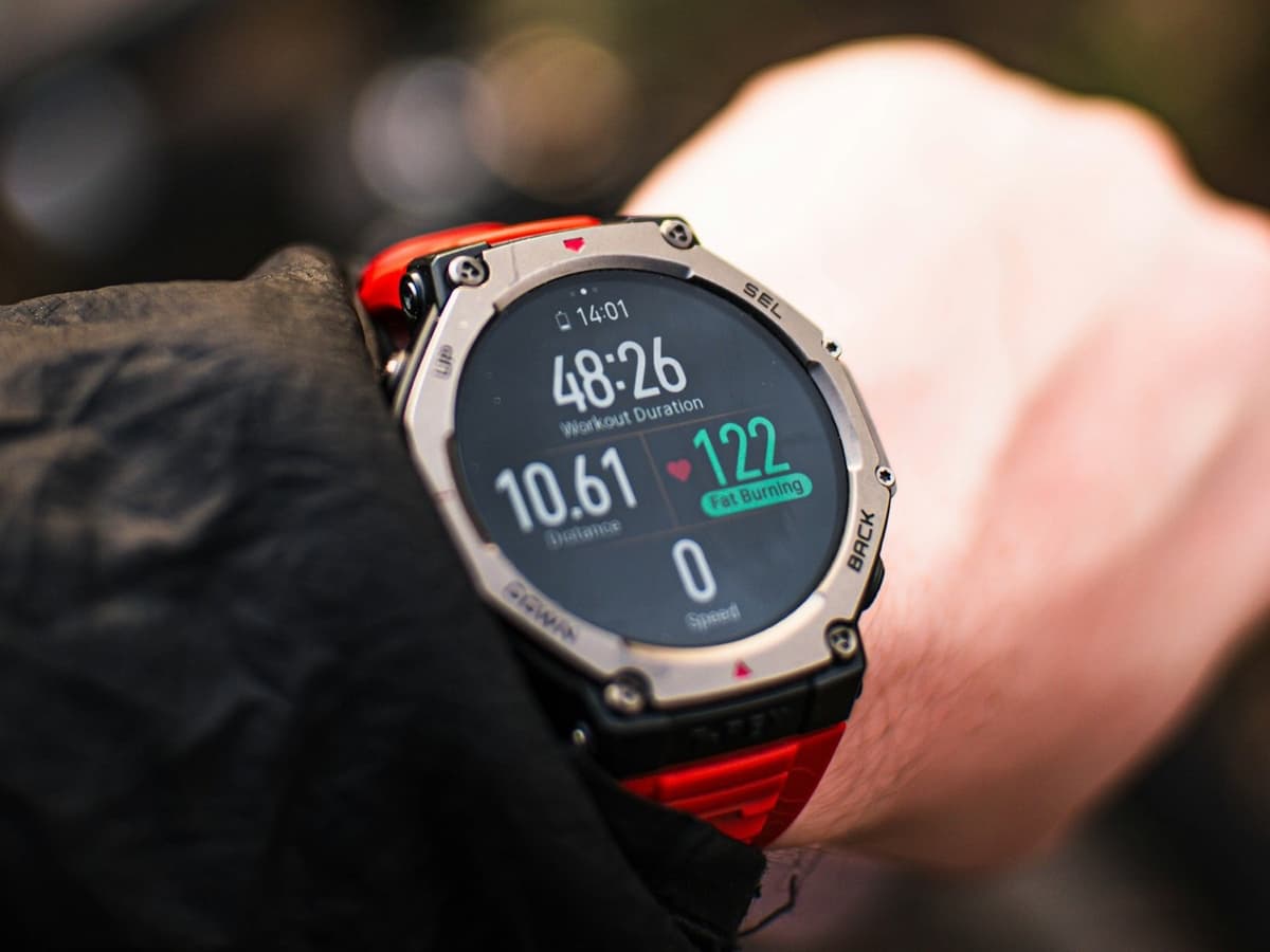 A rugged GPS sports watch on a wrist showing a workout screen with distance and heart rate